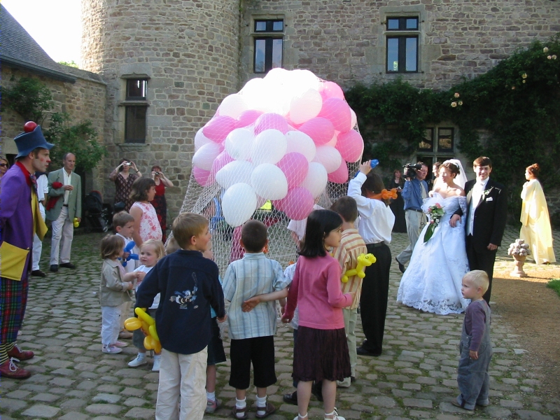 Les mari&eacute;s regardent le clown et les enfants qui pr&eacute;parent le l&acirc;cher de ballons